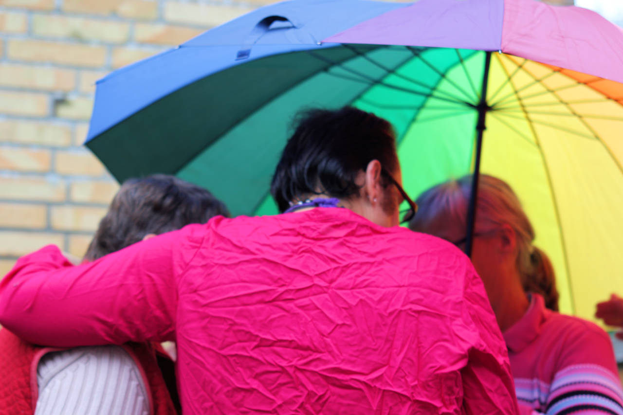 Menschen unter einem Regenschirm in Regenbogenfarben.